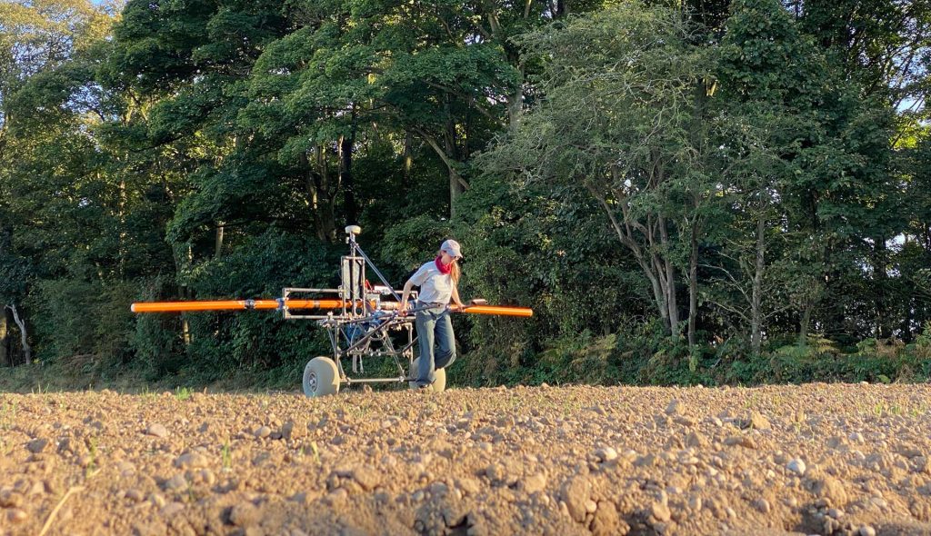 A woman pulling EM equipment in a field